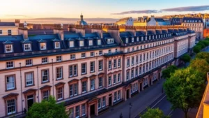 Panoramic view of Edinburgh's New Town showing elegant Georgian townhouses with cream stone facades, tall sash windows, black doors, and tree-lined Heriot Row street at golden hour